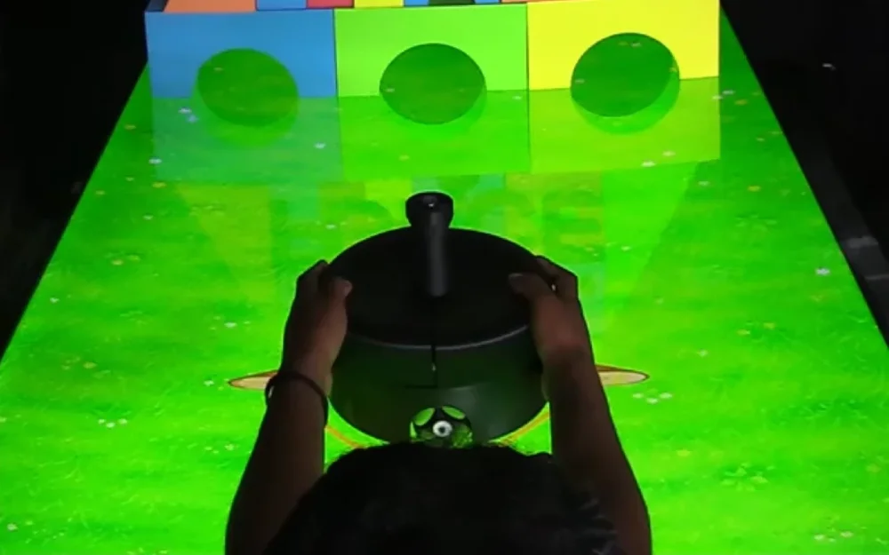 Hands on the KITE haptic robot as it moves across a projected physics scene
